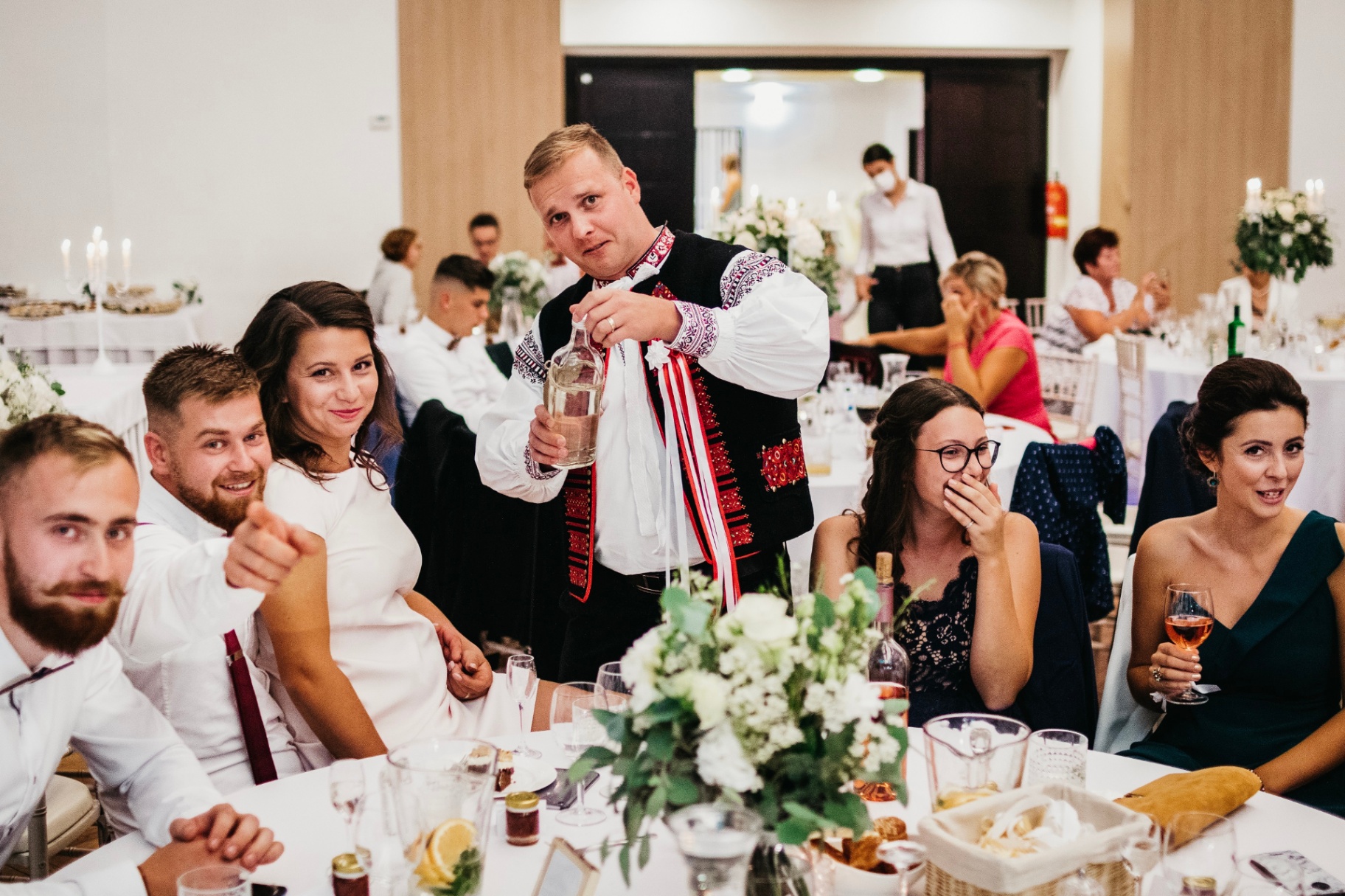 Starejší s fľašou pálenky pri hosťoch